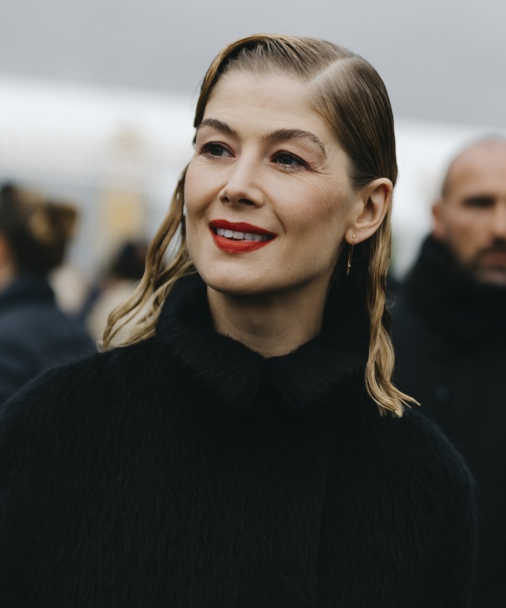 Rosamund Pike with bi-textured bob parted on the side and red lips.