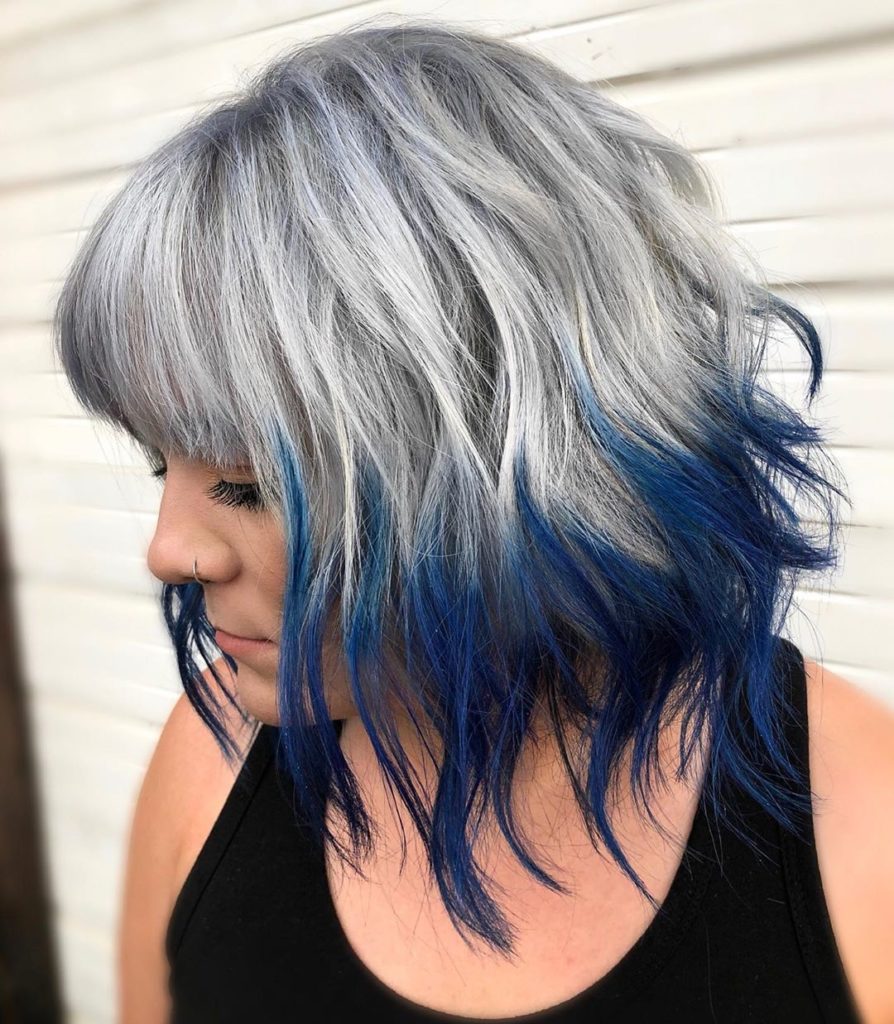 Frisuren mittellang: Frau mit grau gefärbten Haaren und blauen Haarspitzen