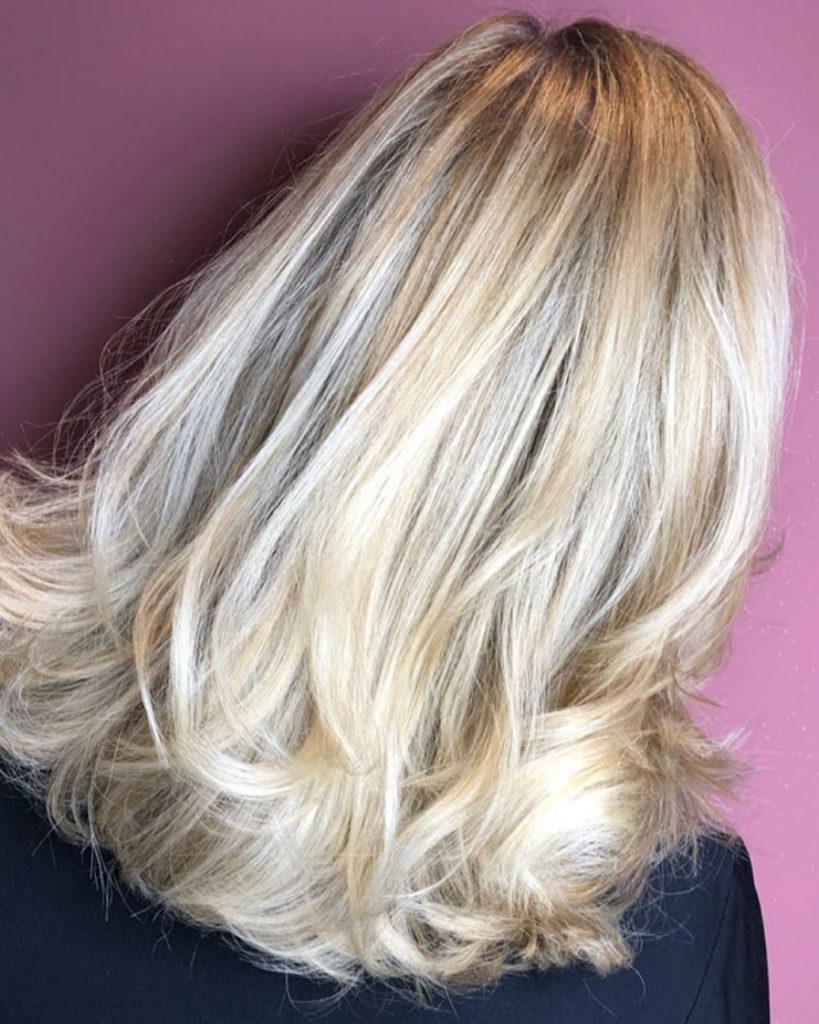 Frisuren mittellang: Frau mit blondem halblangem Haar und leichtem Stufenschnitt