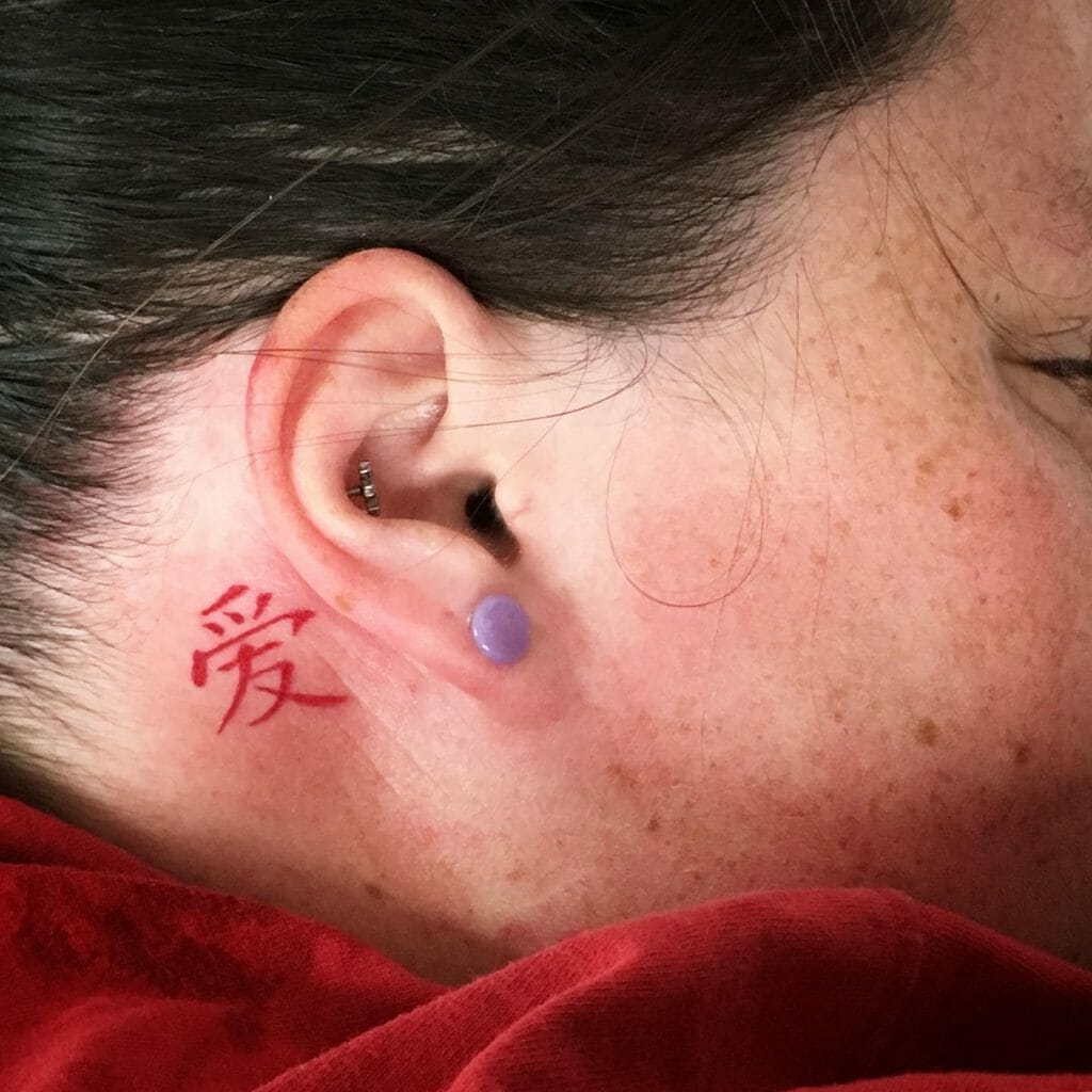 Small red Chinese symbol tattoo behind the ear