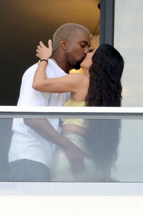 Miami, FL - Couple Kanye West and Kim Kardashian check out their new Miami condo.  The couple, who are expecting their fourth child via surrogate, grabbed the PDA while waving to fans from the balcony.  Image: Kanye West, Kim Kardashian Contains children Please pixelate face prior to publication*