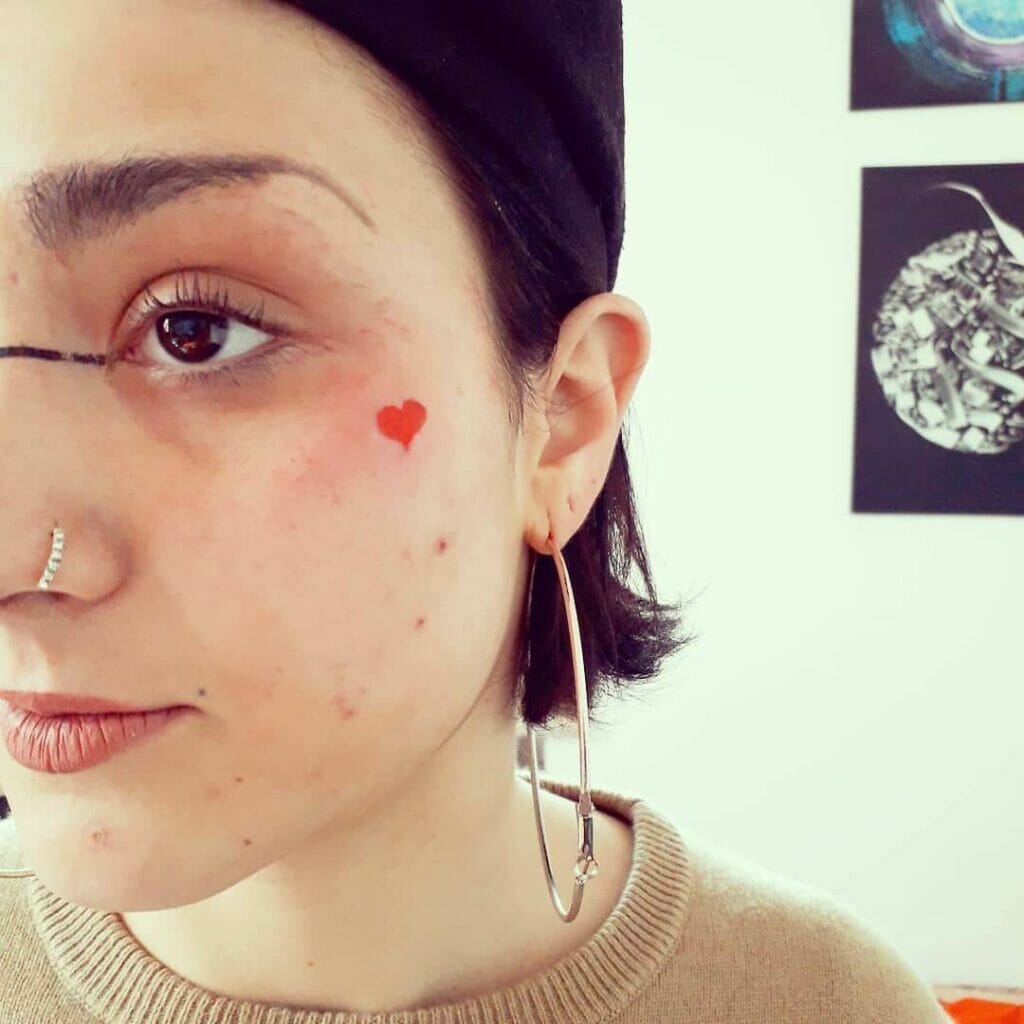 Red heart tattoo on face