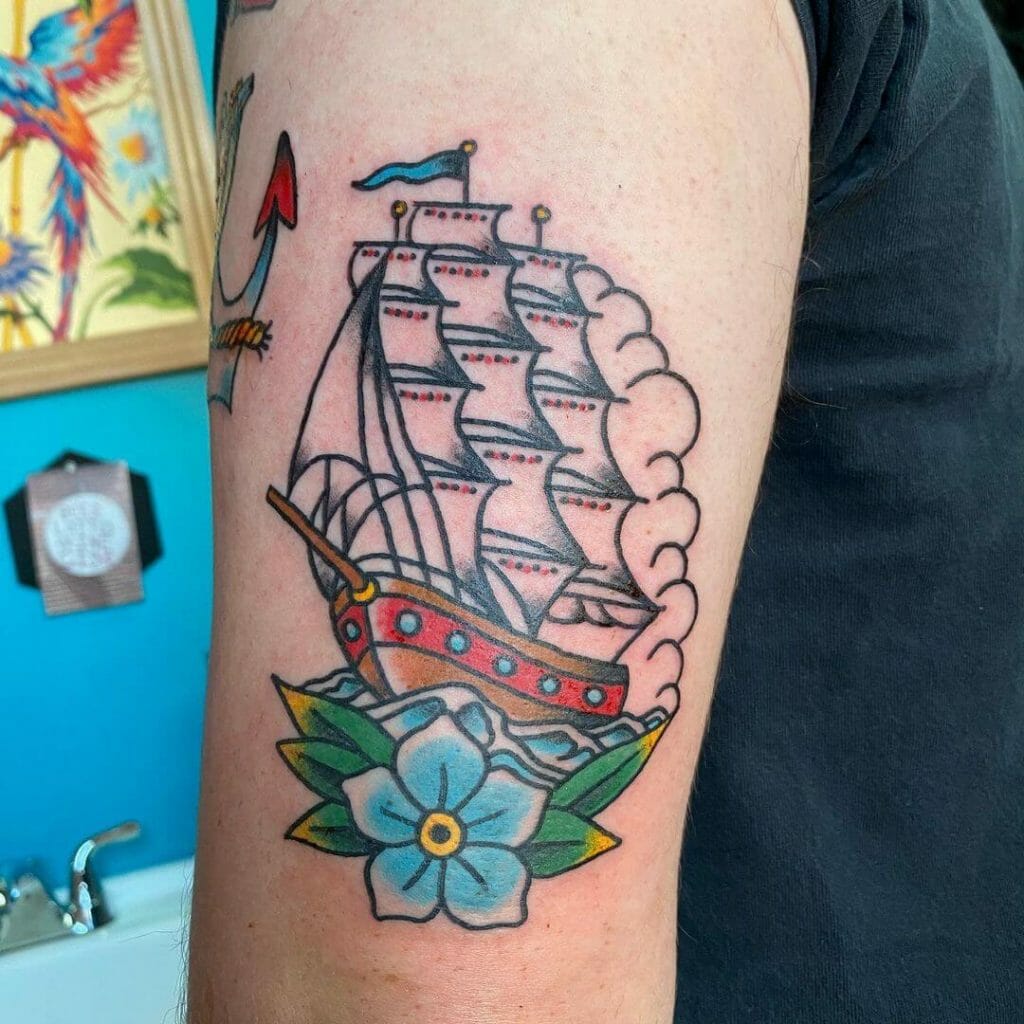 Colorful sailboat tattoo against the backdrop of a sunset