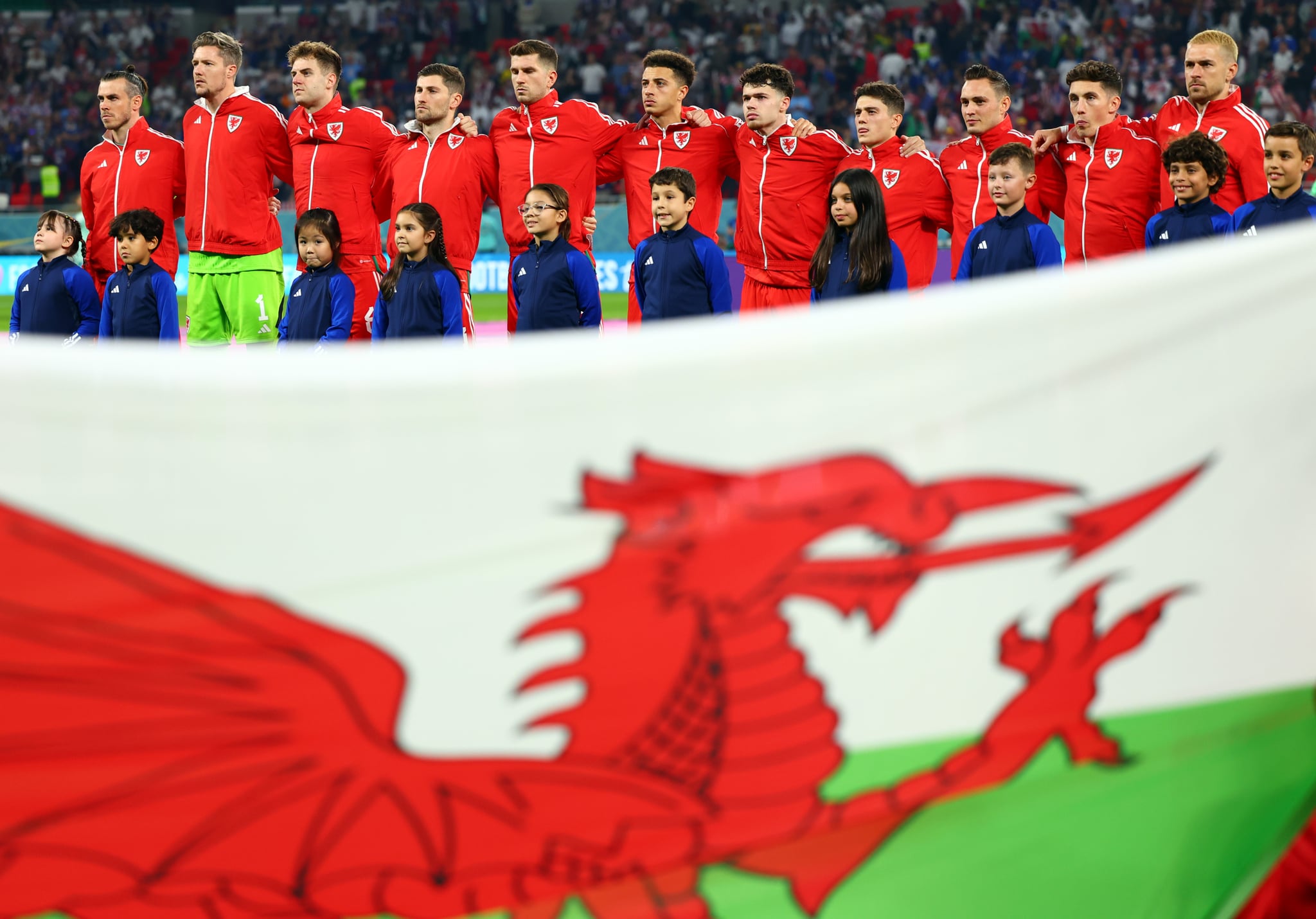 November 21, 2022, Qatar, Ar-Rayyan: Soccer: World Cup, USA - Wales, Preliminary Round, Group B, Matchday 1, Ahmed bin Ali Stadium, Wales players stand behind the Welsh flag with accompanying children before the start of the game.  Photo: Tom Weller/dpa (Photo by Tom Weller/Picture Alliance via Getty Images)