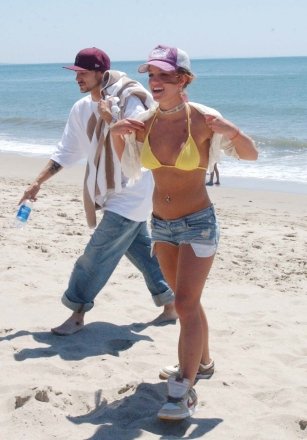 Singer Britney Spears spends the day with an unidentified male friend at Will Rodgers State Beach in Pacific Palisades, California.  The pop princess, who was taking a break from her current US and European tour, had fun frolicking on the beach, piggybacking on her friends' backs and playing with a dog who was walking along the beach.  Britney and her friend then stopped to get some drinks at a local shop before returning to the Beverly Hills Hotel where she was staying before her tour resumes on Monday 2004