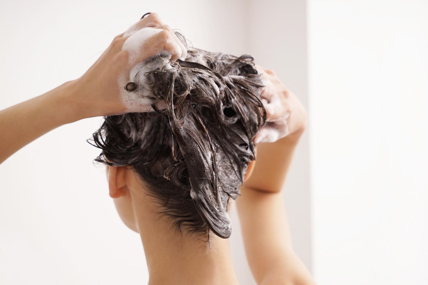 brunette-woman-washes-hair-with-shampoo-against-greasy-hair
