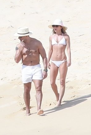 CABO SAN LUCAS, MEXICO - *EXCLUSIVE* - The mother-of-three showed off her rock-hard physique in a tiny white bikini while strolling on the beach with husband Mark Consuelos.  Image: Kelly Ripa and Mark Consuelos Contains children Please pixelate face prior to publication*