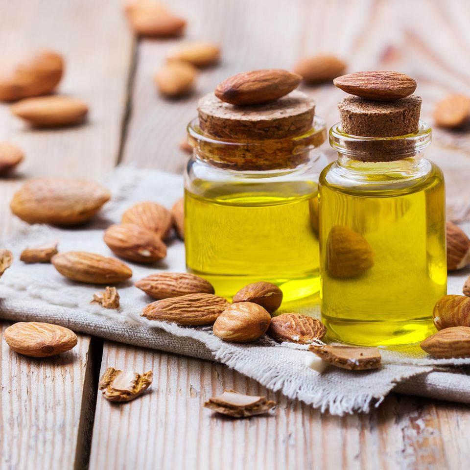 Bottled almond oil and surrounding whole almonds