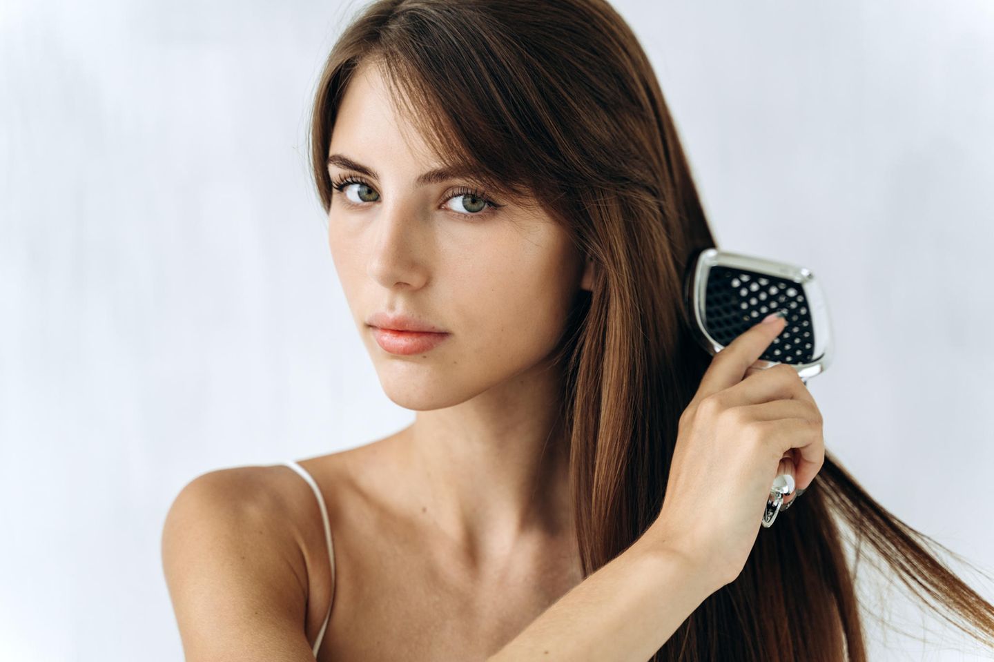 brunette woman straightens her hair with a straightening brush