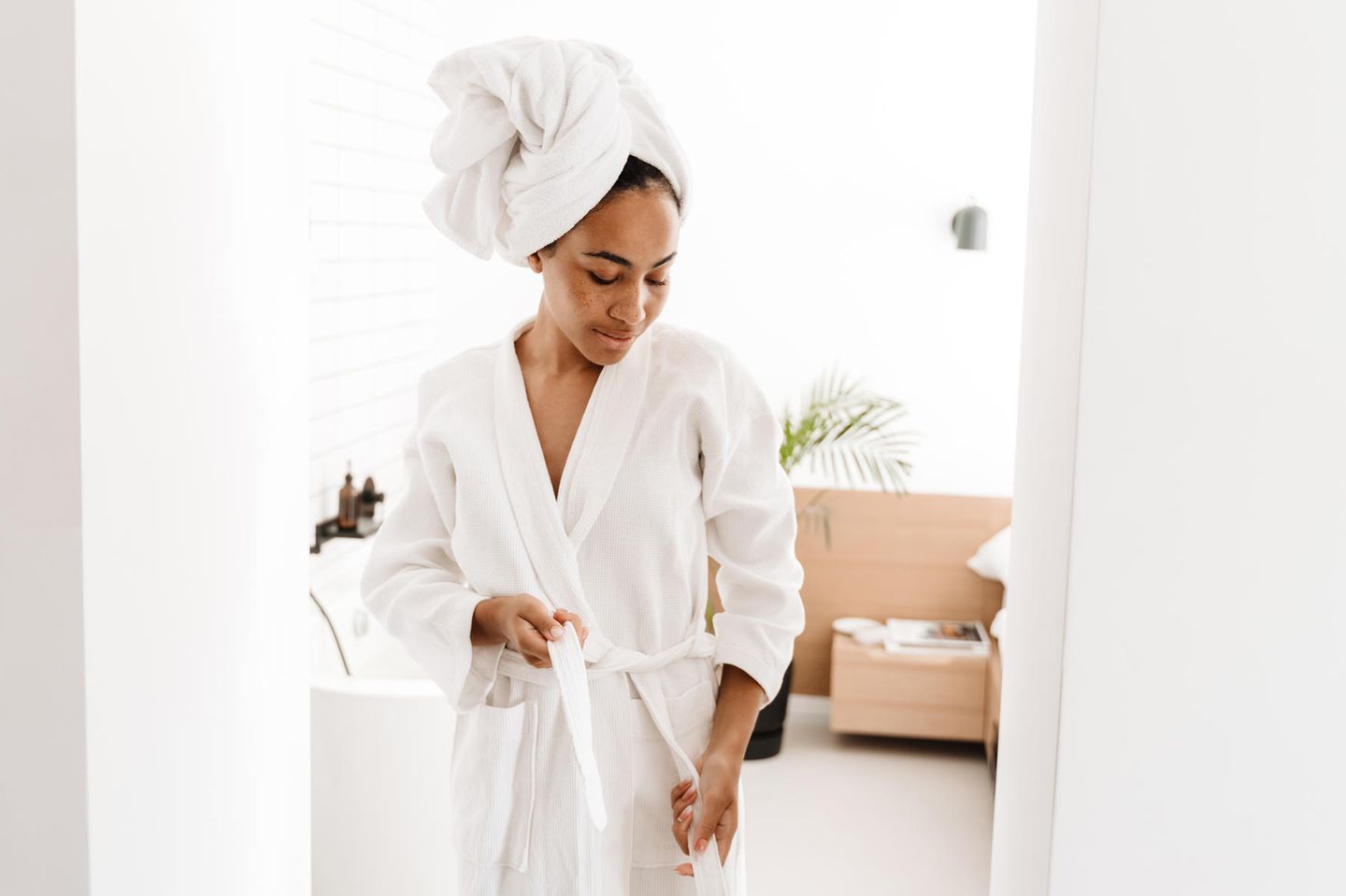 Intimate hygiene: woman ties her bathrobe in the bathroom